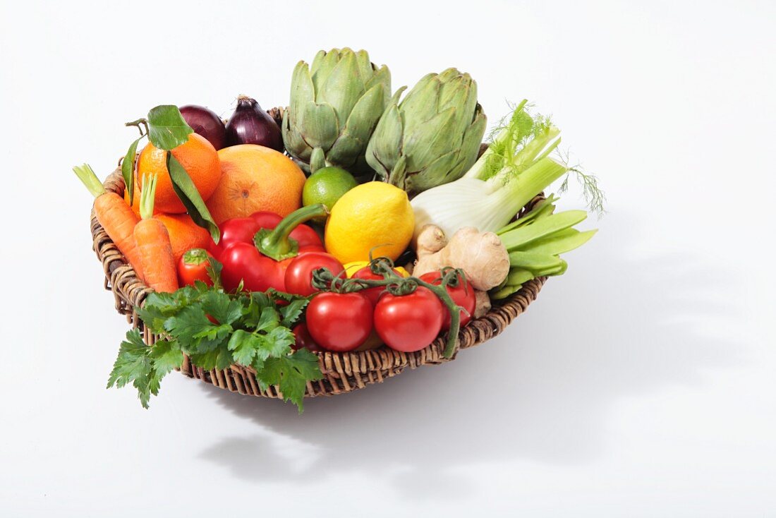 A basket of vegetables with citrus fruits and ginger