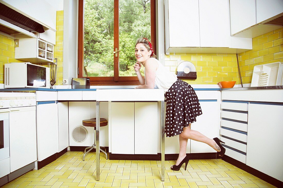 A young woman in a vintage kitchen wearing 1950s style clothing