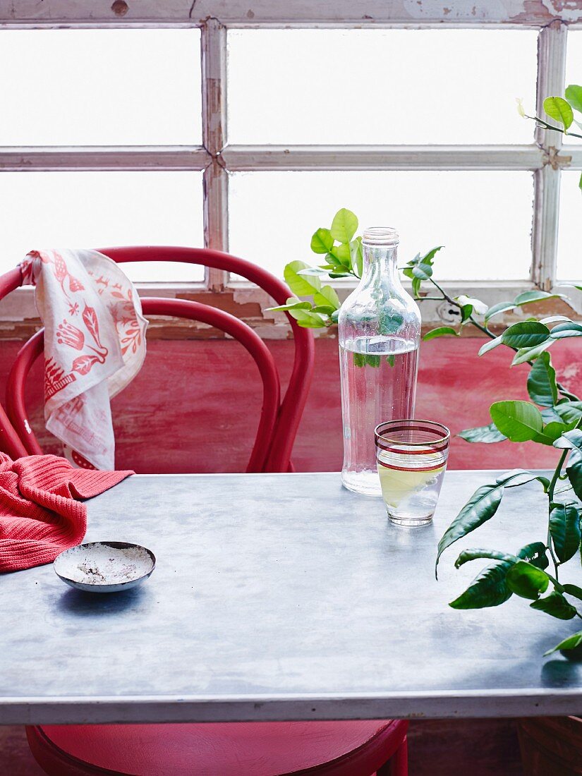 A carafe of water and a glass of water with a slice of lemon on a table