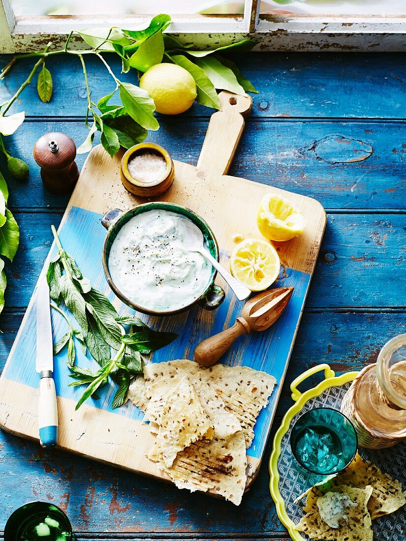 Tzatziki with unleavened bread on chopping board