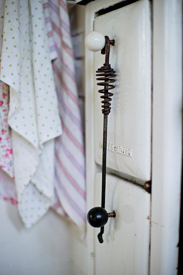 Detail of white, enamel, vintage solid fuel stove in kitchen with spherical door handles