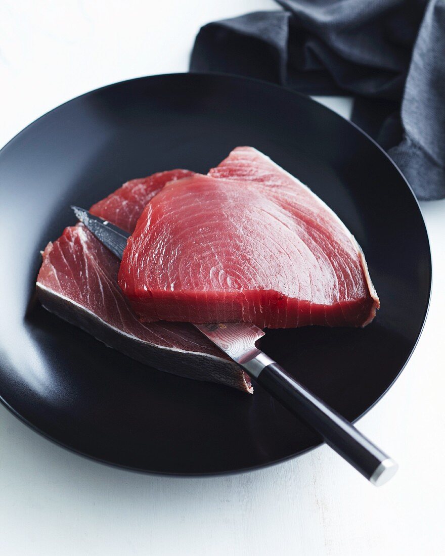 Frische rohe Thunfisch Steaks auf schwarzem Teller