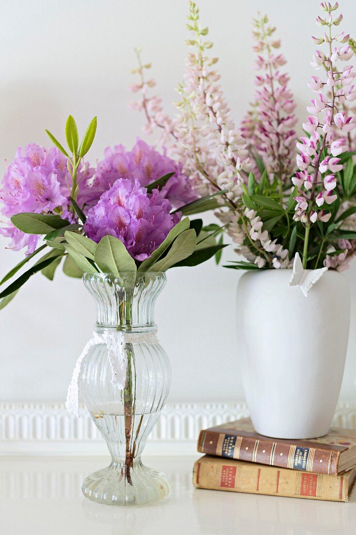 Blumen in Vasen und Bücher auf weisser Ablage