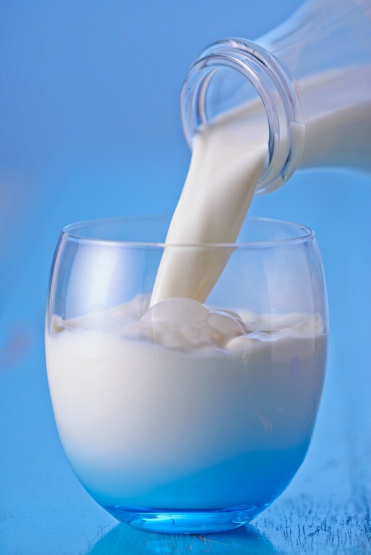 Milk Pouring From a Bottle into a Glass