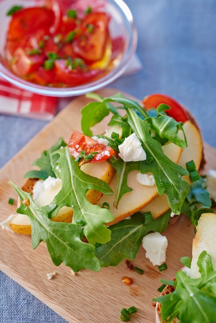 Belegtes Brot mit Rucola, Birnen, Feta und Tomaten