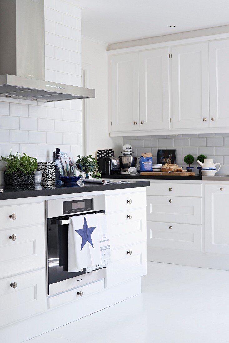 White, Scandinavian-style kitchen with black worksurface; tea towel with star motif
