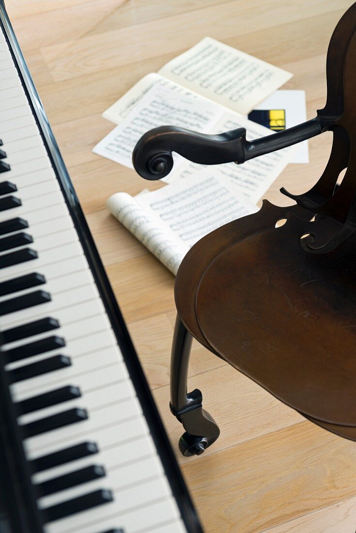 Piano keyboard, vintage armchair and sheet music lying on floor