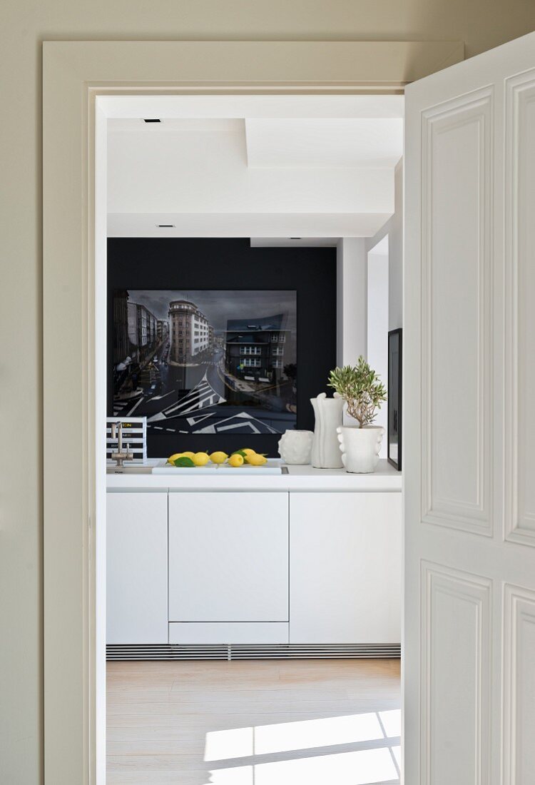 View through open door into modern kitchen with white counter and photographic art