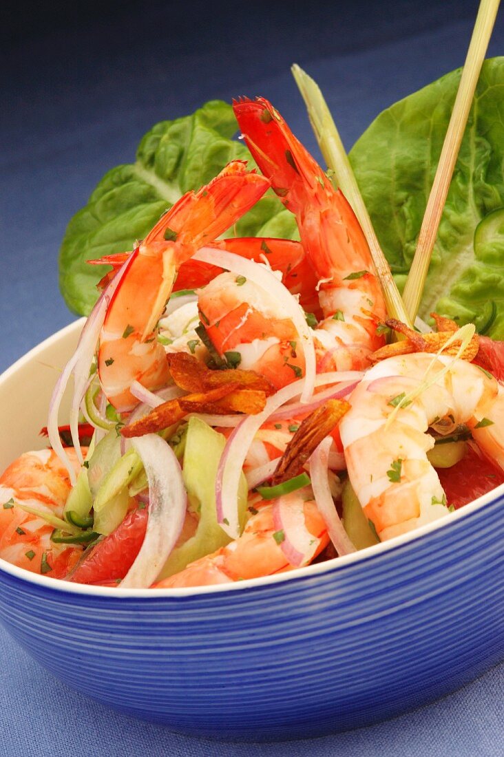 Exotic prawn salad with vegetables in a blue bowl