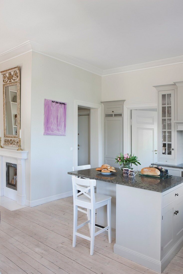 Pale grey island counter and bar stool in open-plan, country-house kitchen