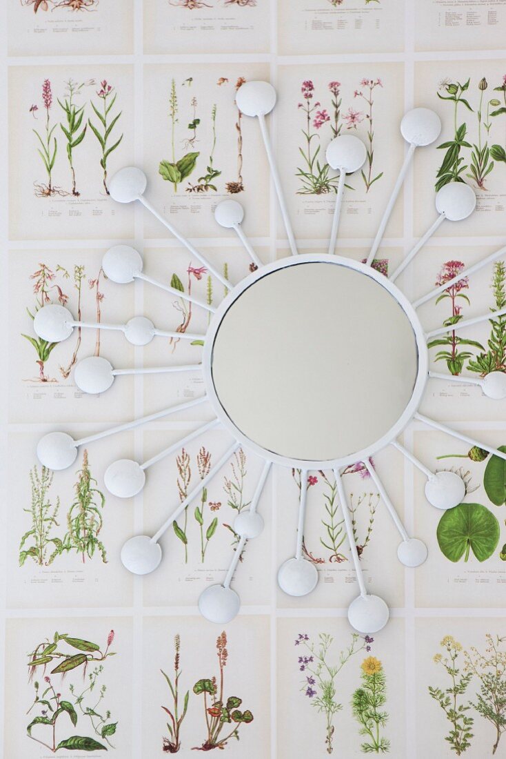 Sunburst mirror on wallpaper with botanical pattern