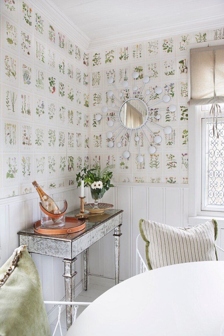 Delicate console table against wall with white wainscoting and botanical wallpaper