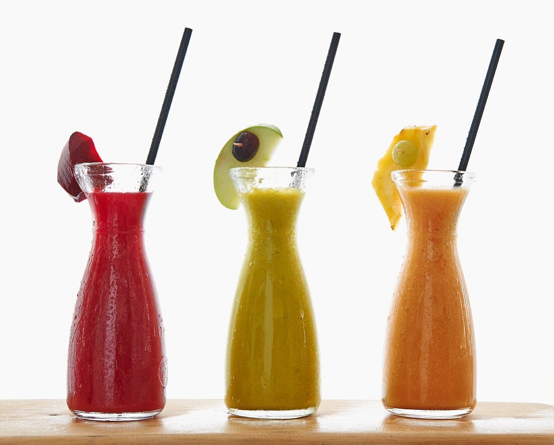 Three different smoothies in carafes