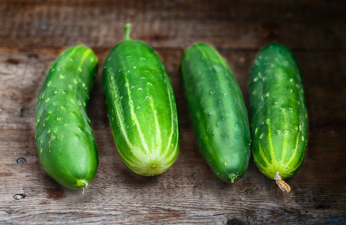 Four cucumbers on a wooden surface