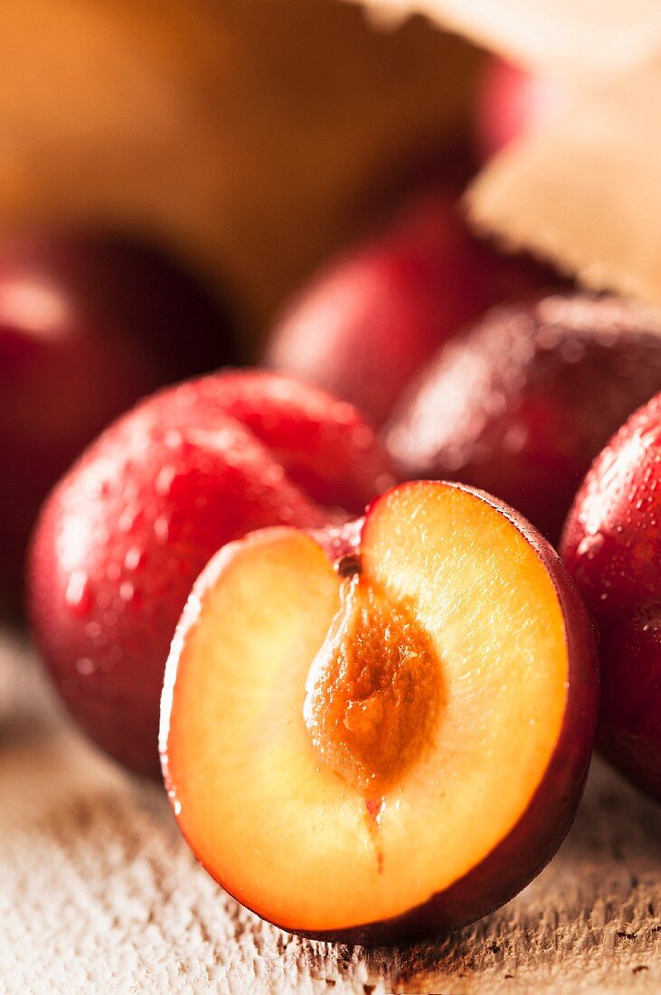 Rote Pflaumen mit Wassertropfen, ganz und halbiert