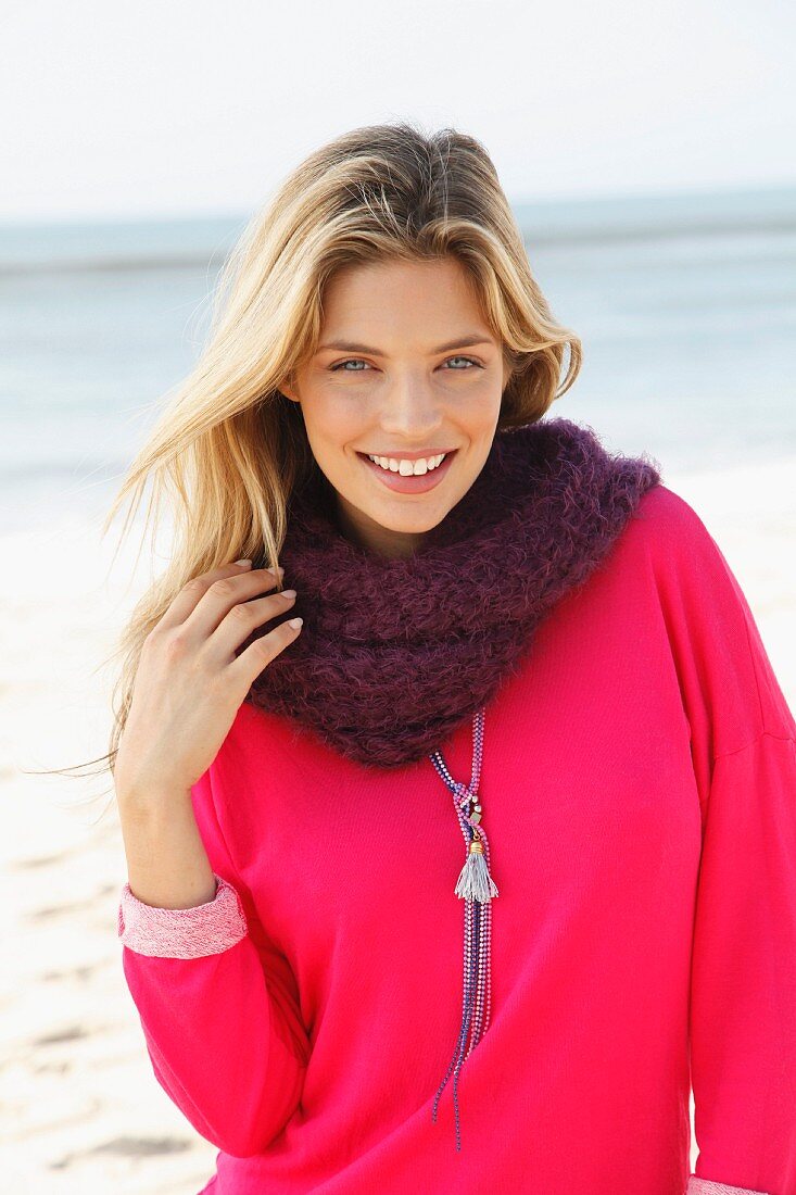 A young blonde woman wearing a pink sweatshirt and a scarf