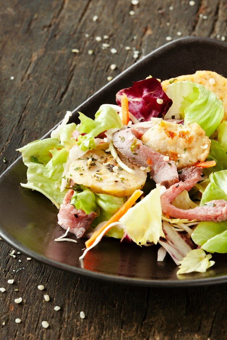 Salat mit Semmelknödelscheiben und Roastbeef