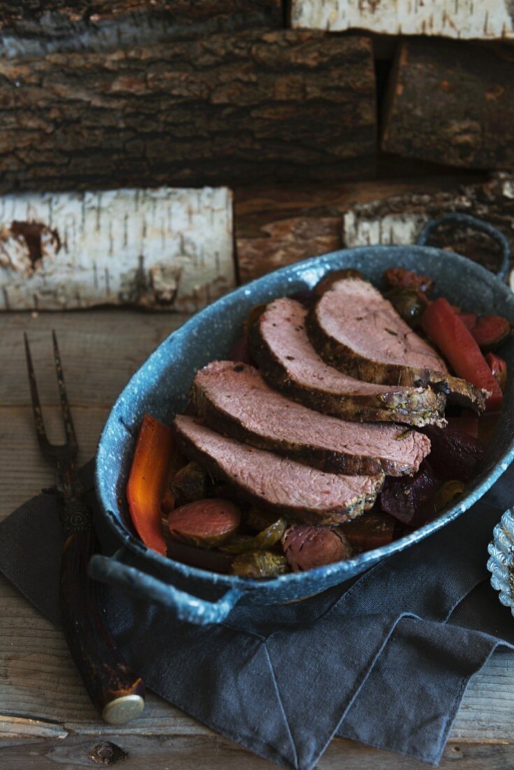 A Whole Chuck Roast, Partially Sliced on a Platter with Veggies