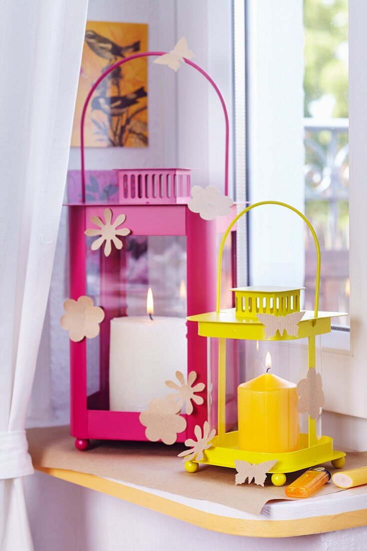 Lanterns on windowsill decorated with punched paper flowers and butterflies