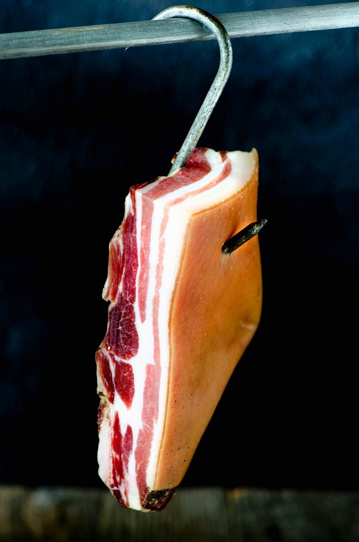 Pancetta hängt an einem Fleischerhaken (Italien)