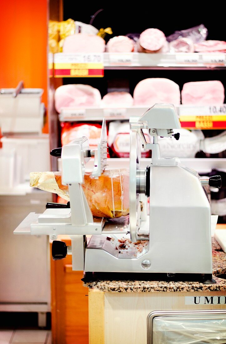 Schneidemaschine mit einem Parmaschinken auf der Fleischtheke eines italienischen Supermarkts