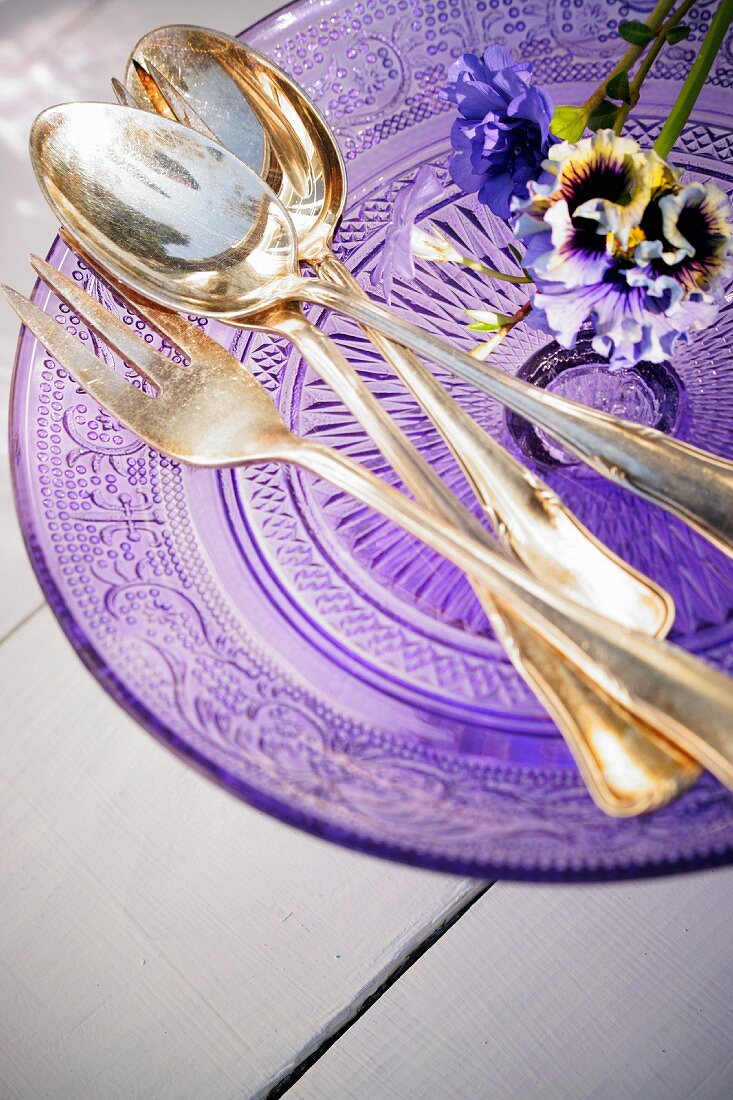 Purple flowers and silver cutlery on a glass purple plate