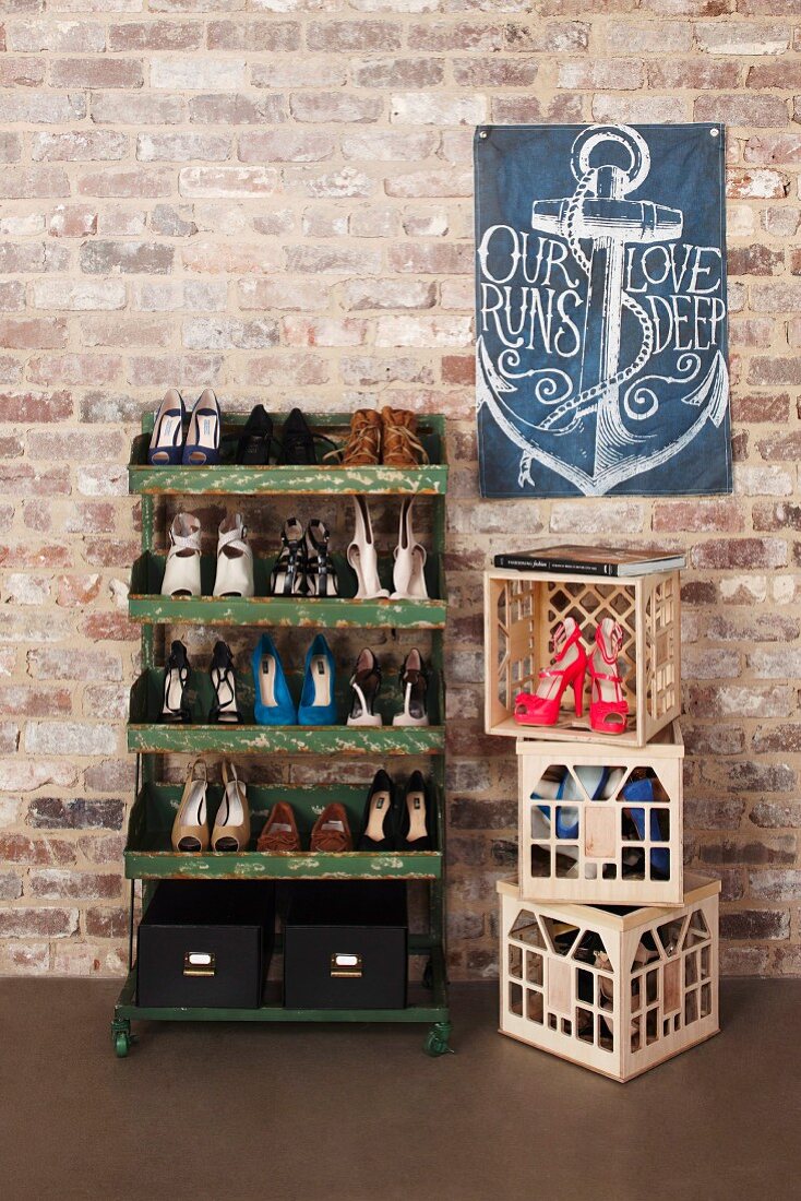 Ladies' shoes on vintage metal shelves and in plastic bottle crates below flag with anchor motif on brick wall