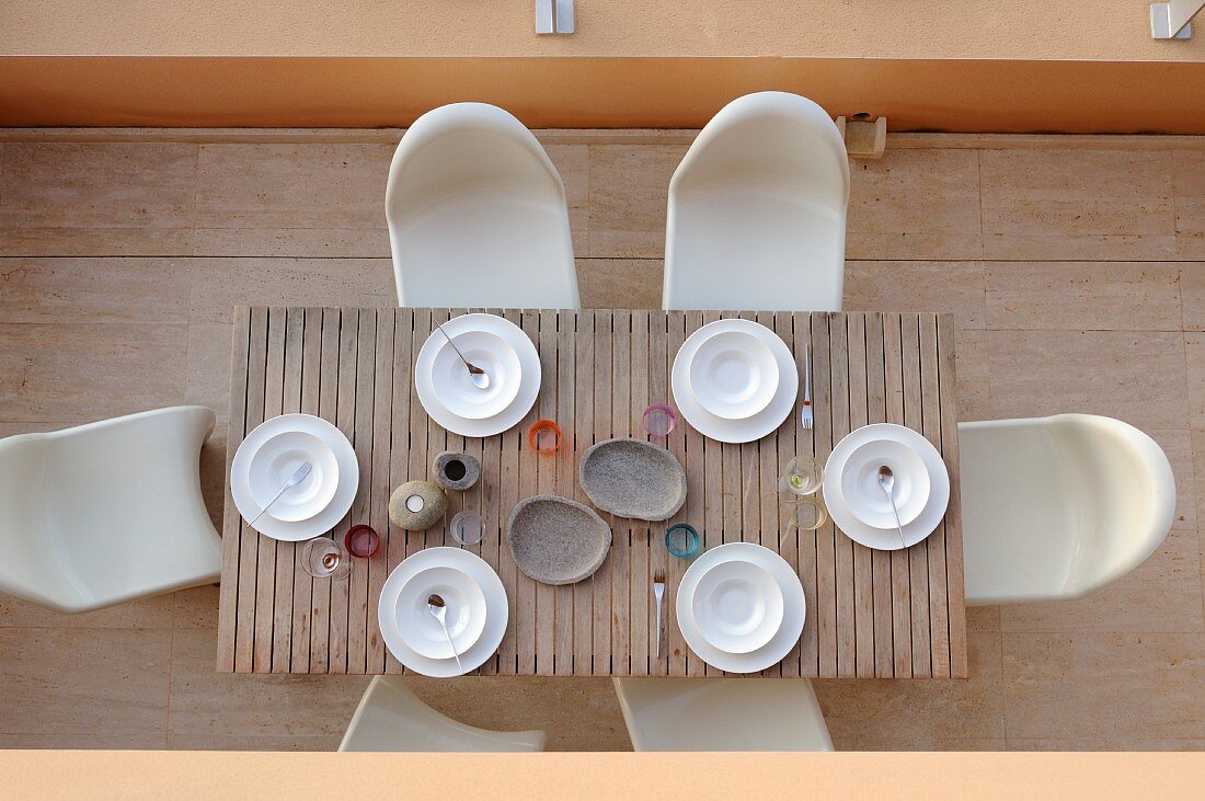 Birdseye view of terrace with simply set wooden table and Panton chairs