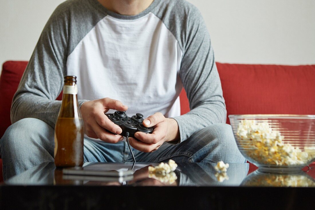 A middle-aged man sitting on a sofa with a computer game console