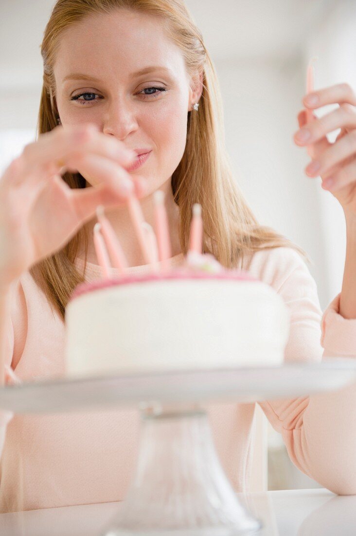 A woman putting candles on a birthday cake