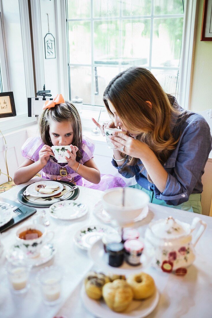 A mother and daughter having tea in a dining room