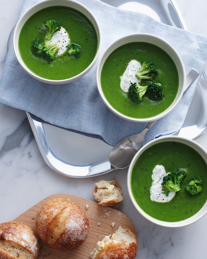 Three bowls of broccoli soup with sour cream