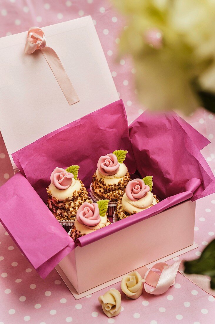 Cupcakes mit weißem Schoko-Topping und Zuckerrosen zum Verschenken