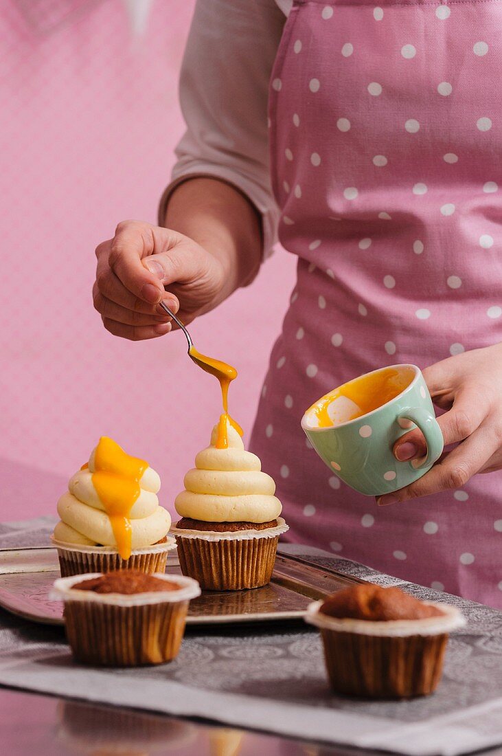 Cupcakes being decorated with mango sauce