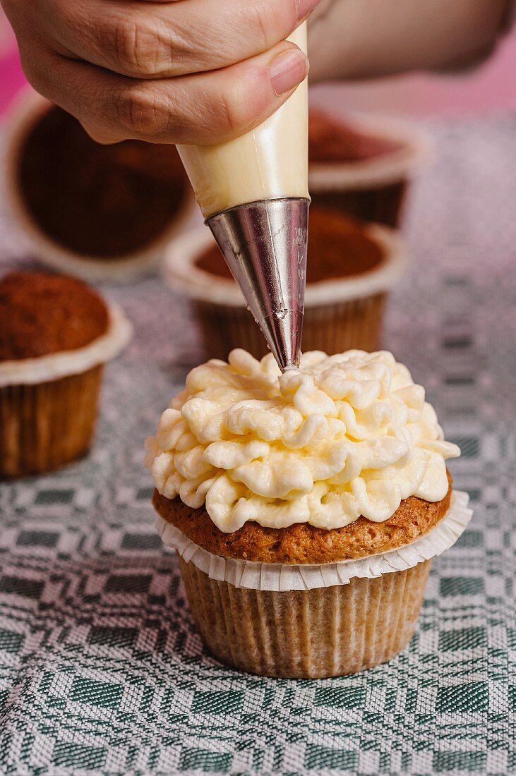 Cupcakes being decorated with butter cream