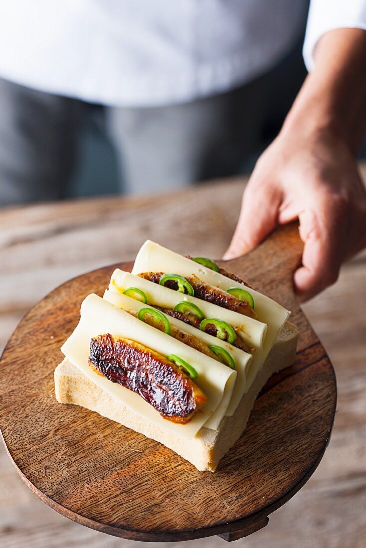 A cheese sandwich with fried banana on a wooden plate