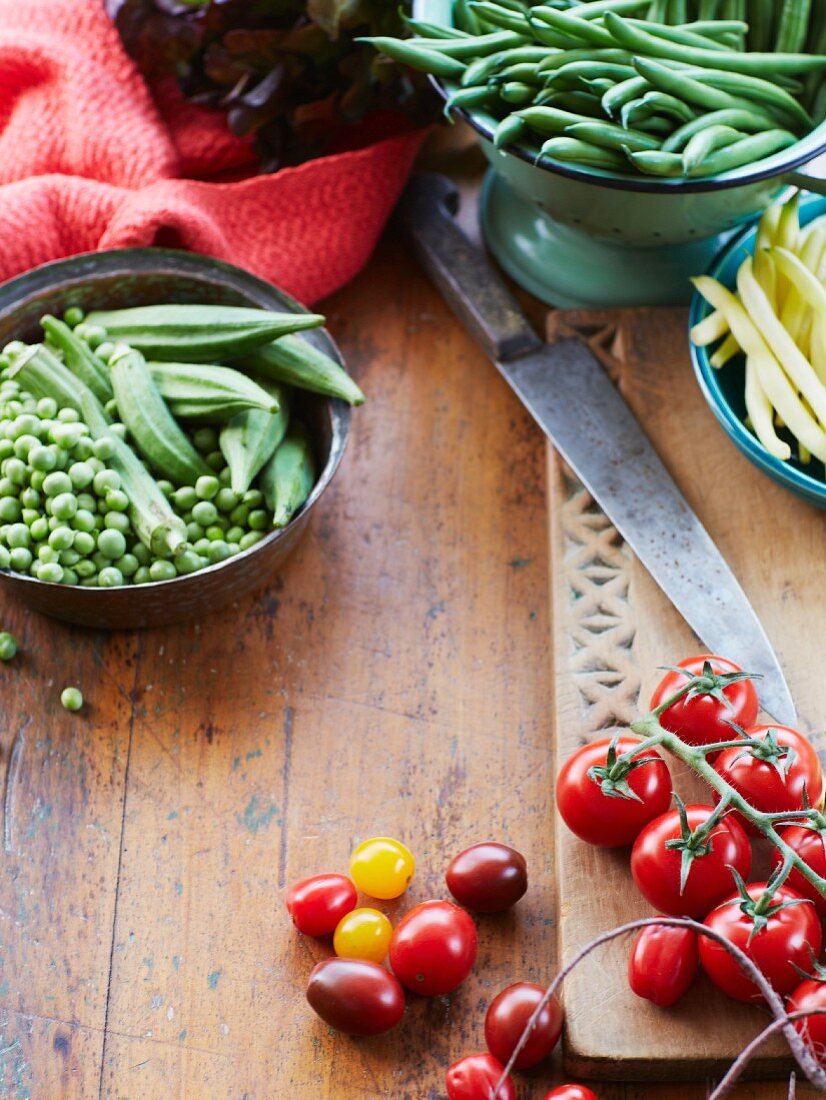 Gemüsestillleben mit frischen Strauchtomaten, Erbsen und Okra