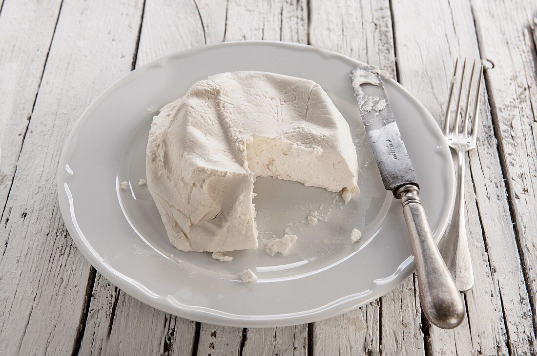 Ricotta auf weißem Teller mit Messer