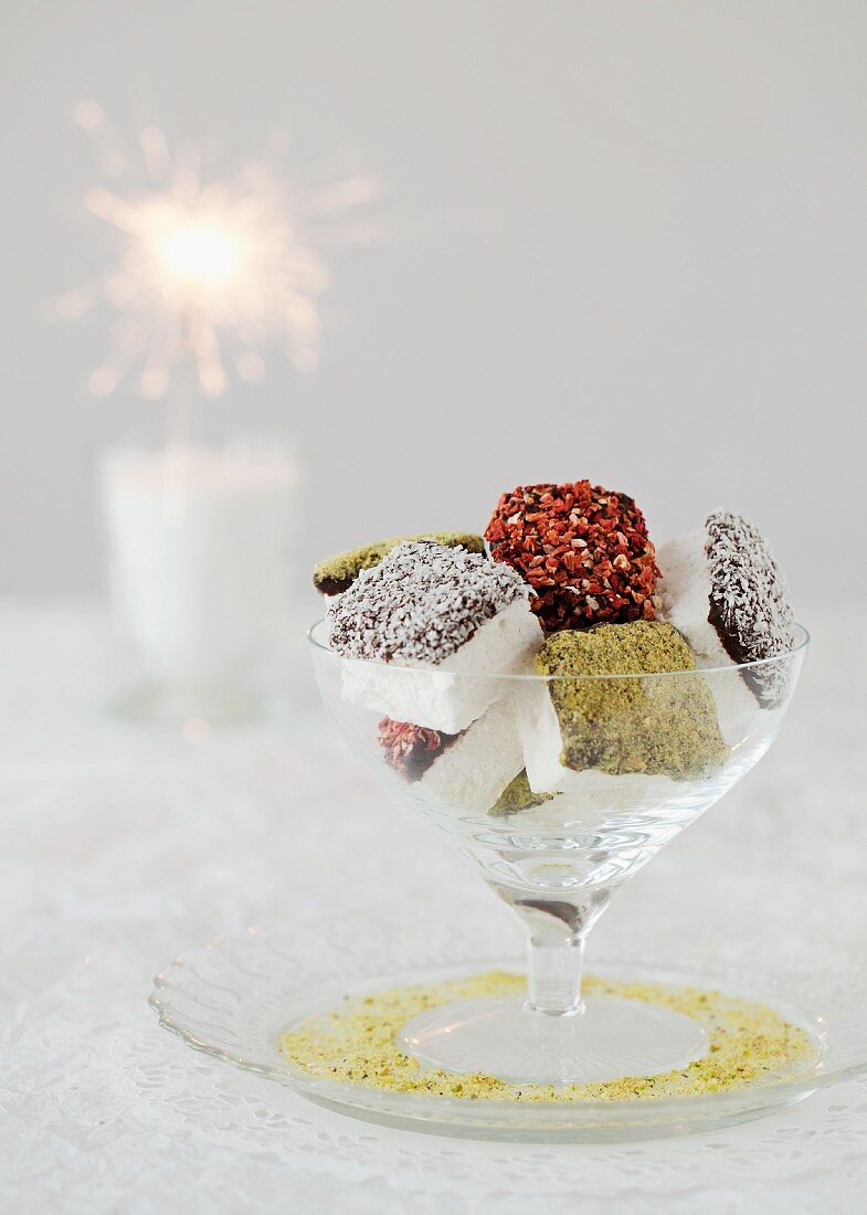 Chocolate-covered, coated marshmallows in a glass bowl with a sparkler in the background