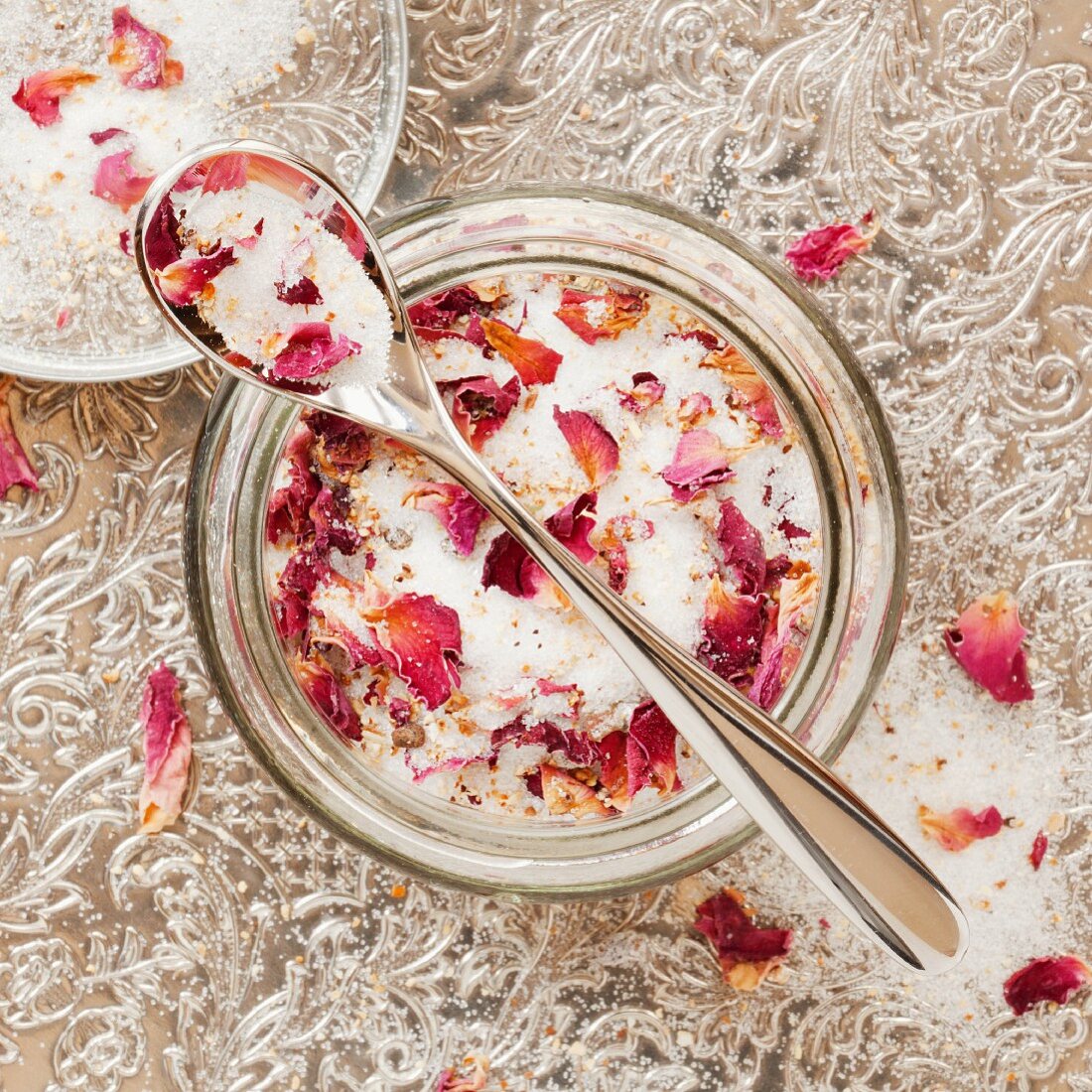 Rose scented sugar in a glass bowl with a spoon on a silver tray