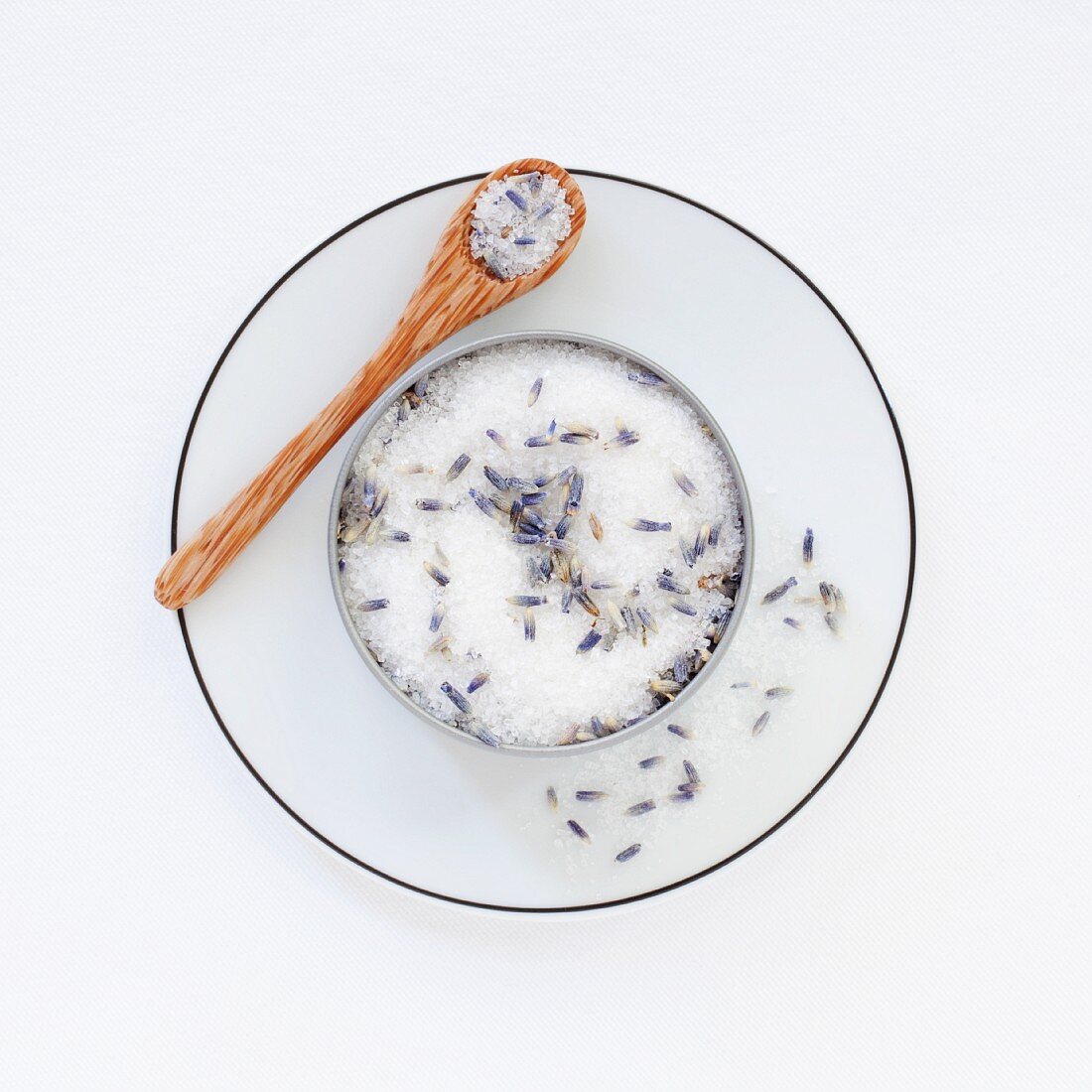 A pot of lavender sugar on a saucer with a spoon