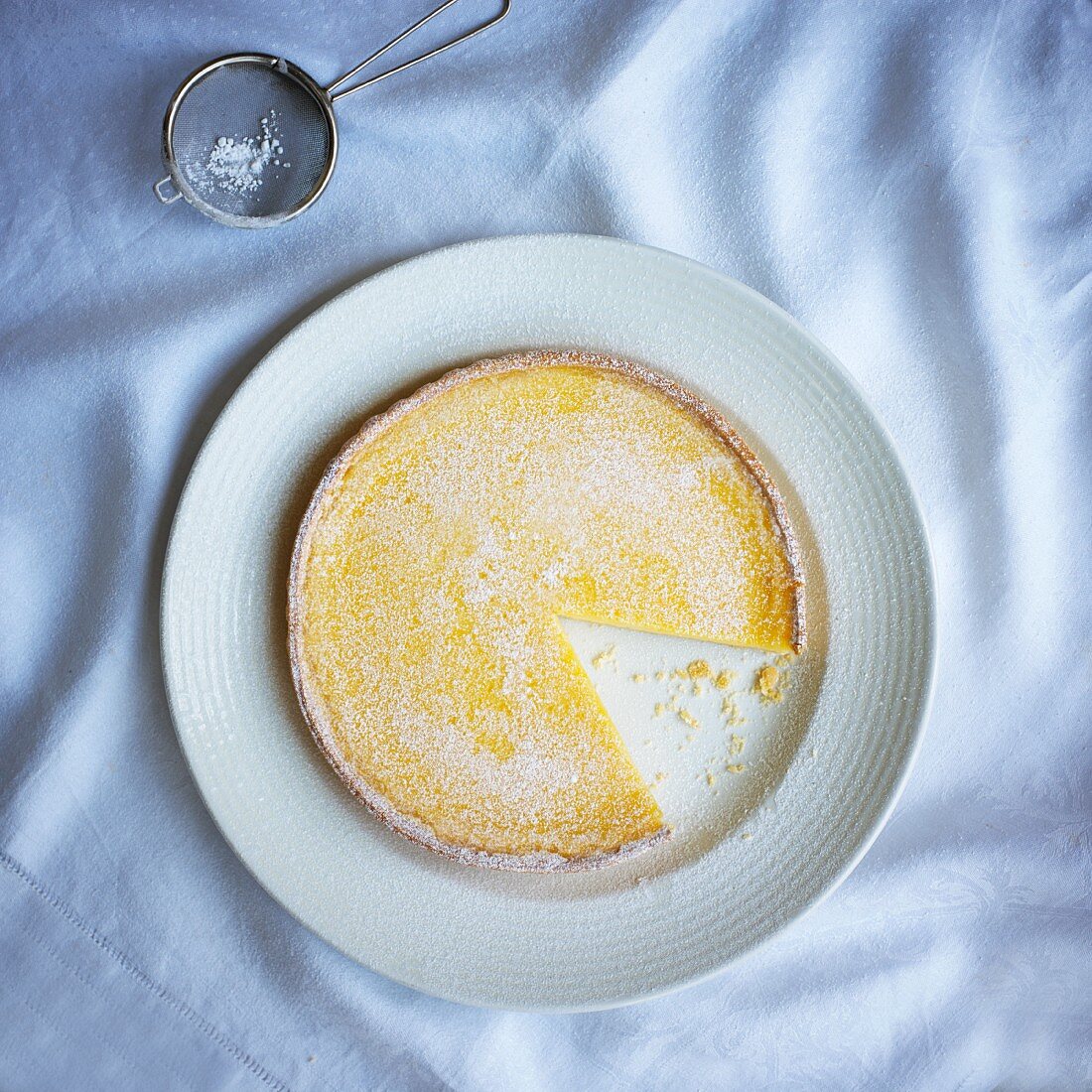 Lemon tart with icing sugar, sliced (seen from above)