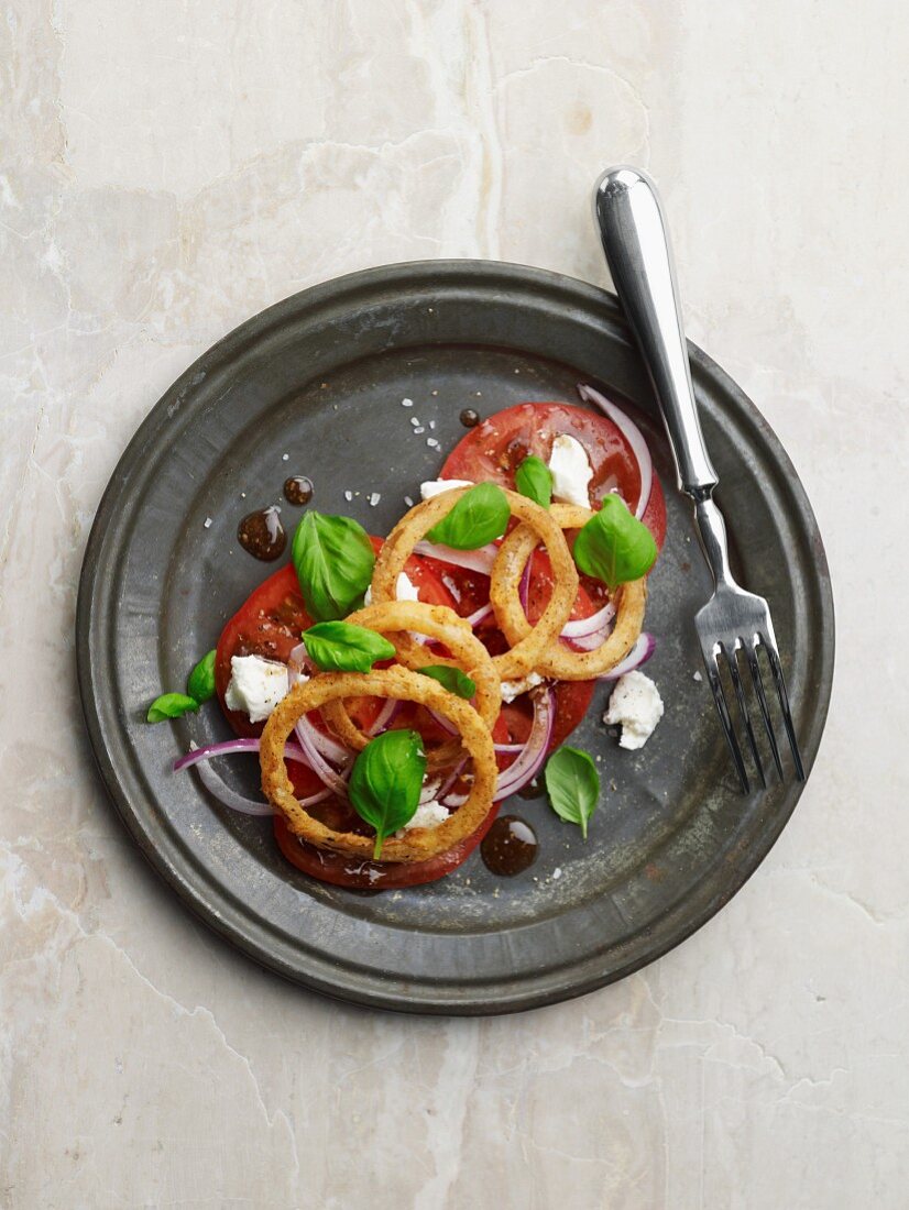 Frittierte Zwiebelringe mit Ziegenkäse auf Tomaten