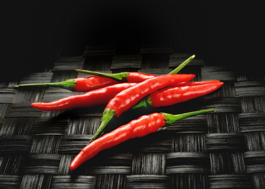 Red chilli peppers on a black woven mat