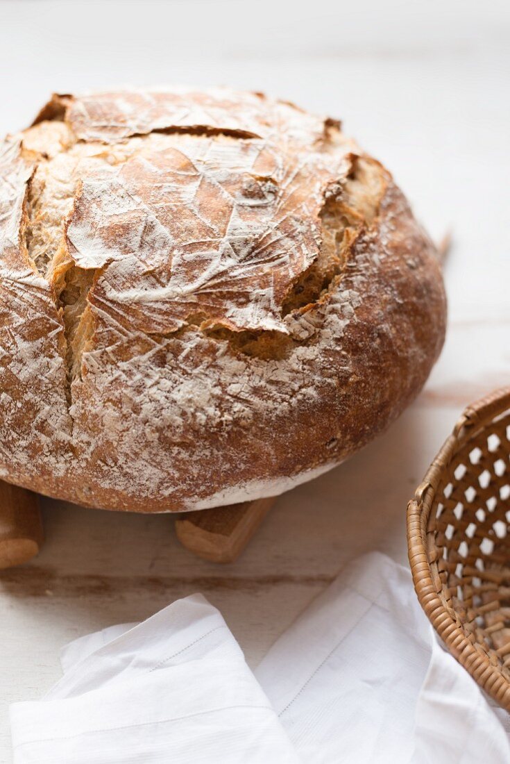 A rustic loaf of bread next to a bread basket