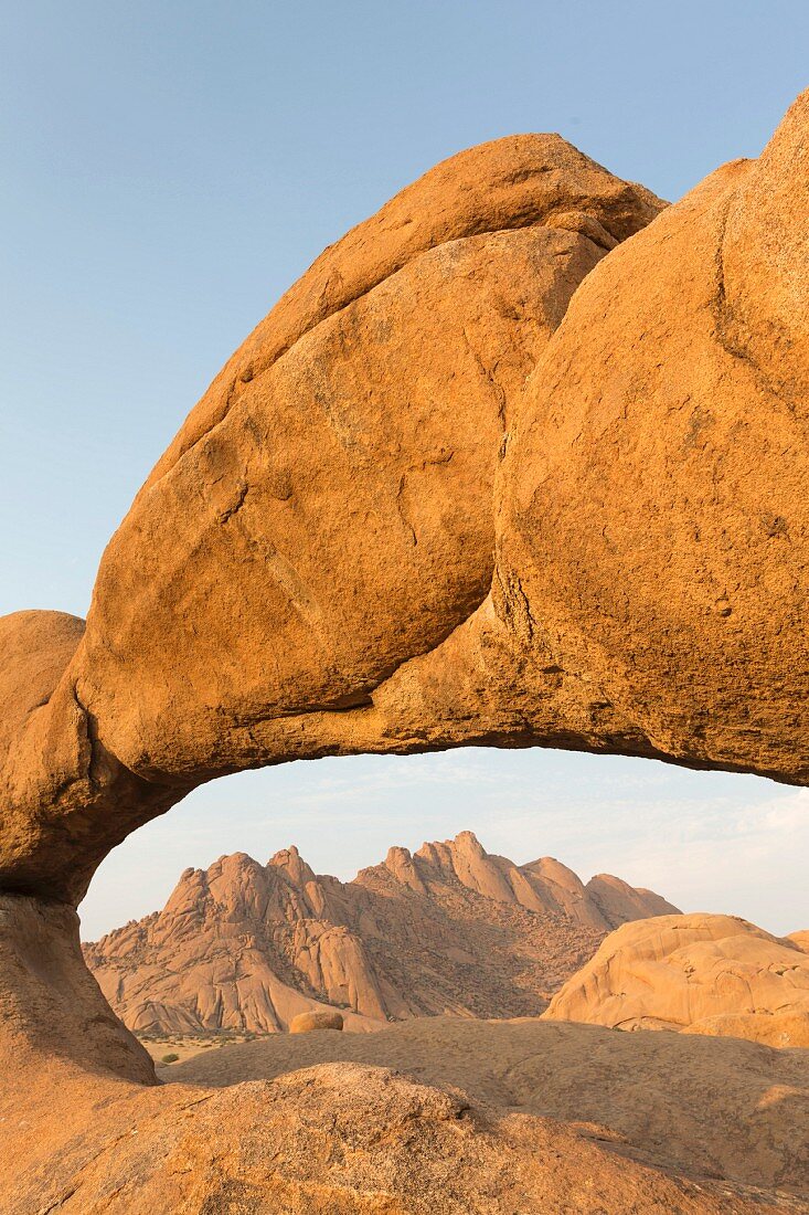 'Rock Arch' in the Spitzkoppe region with a view of the Pondok mountains, Erongo mountain range, Namibia