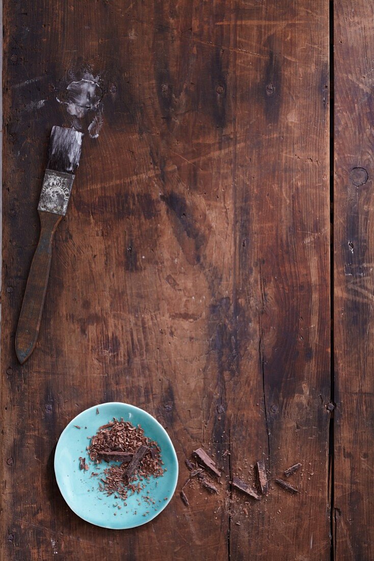 Icing sugar on a baking brush and a bowl of grated chocolate