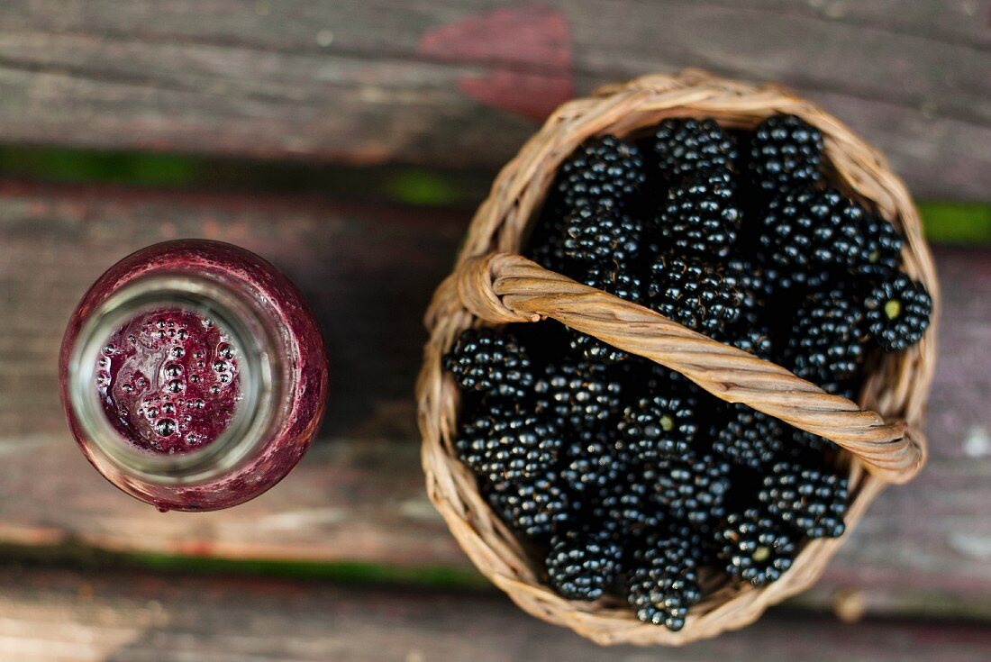 A blackberry smoothie and a basket of fresh blackberries