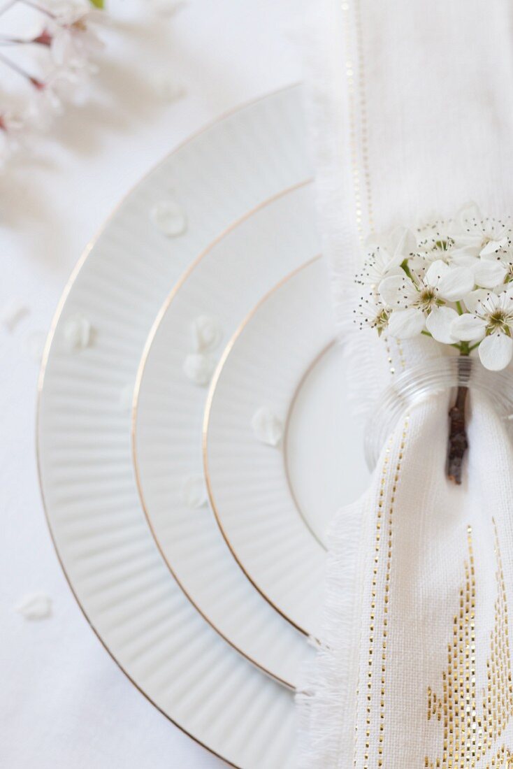 A white place setting decorated with apple blossom on a wedding party table