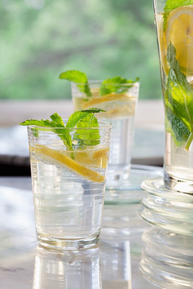 Lemon water with mint in two glasses and a jug